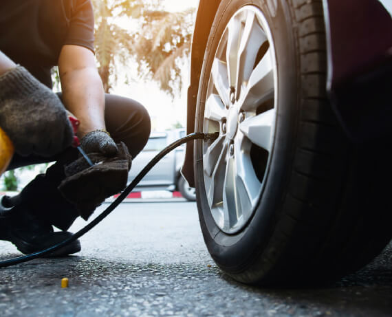 Technician inspecting car tire for punctures, air leaks, and tread damage at The Tire Studio