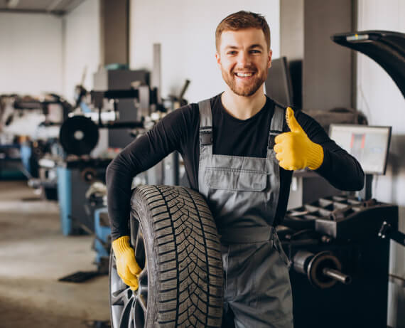 Experienced technician repairing a car tire using professional tools at The Tire Studio